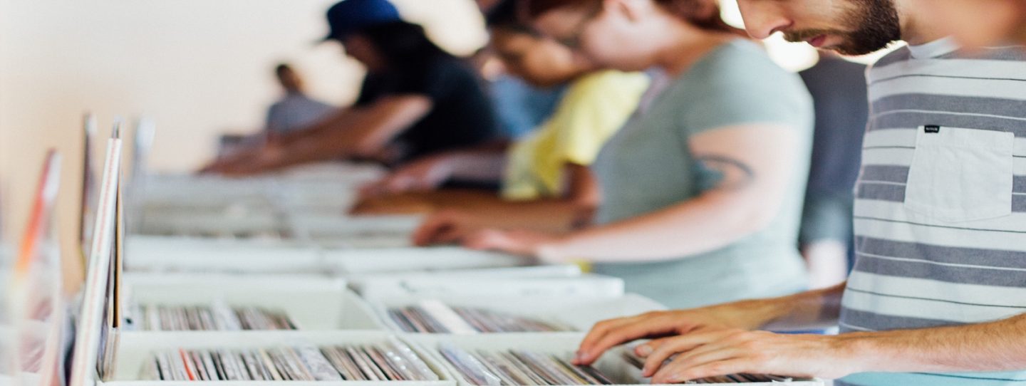 people searching through boxes of vinyl records in a line