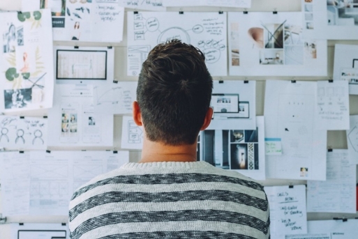 a man looking a notes pinned on a wall and analyzing