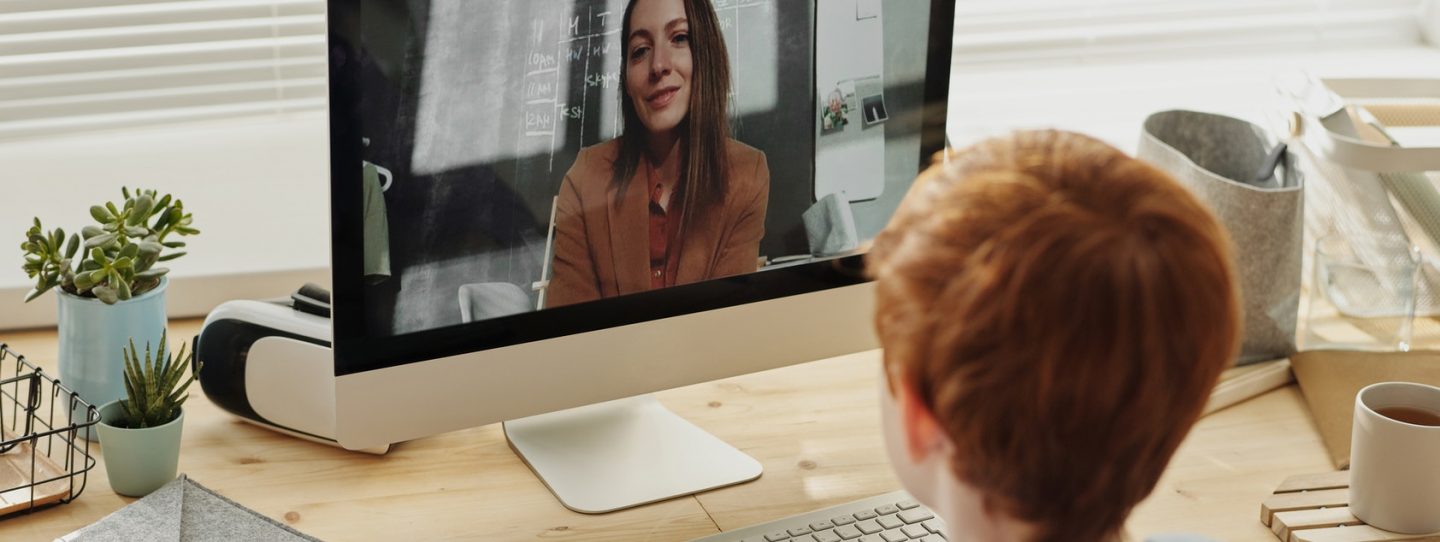 a boy watching a video of a woman speaking on an educational topic on screen