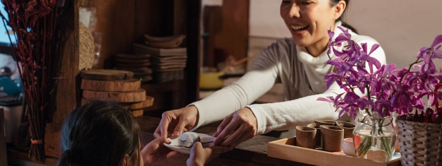 smiling lady serving cupcake to a girl customer